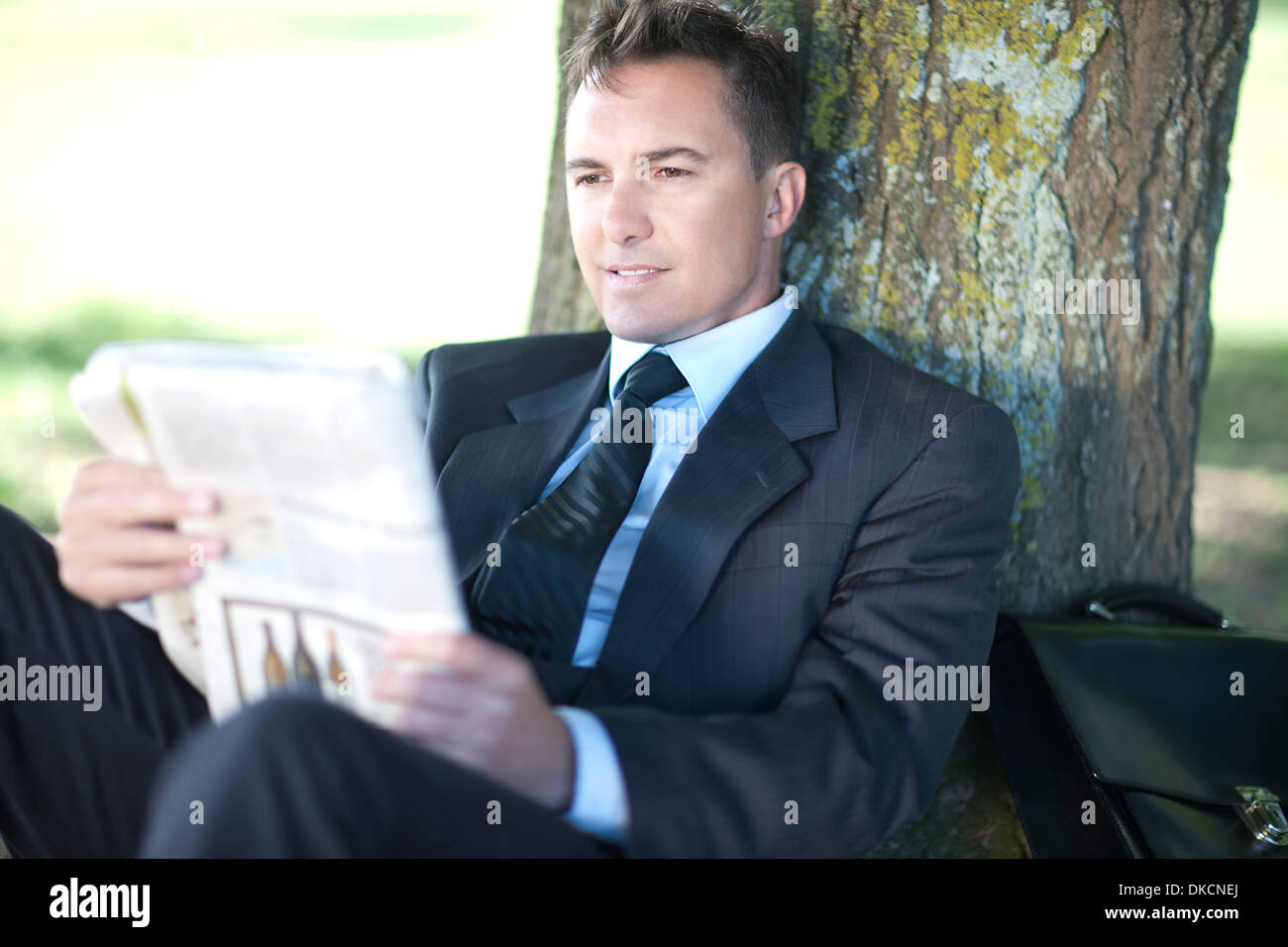 Businessman reading under tree Banque D'Images