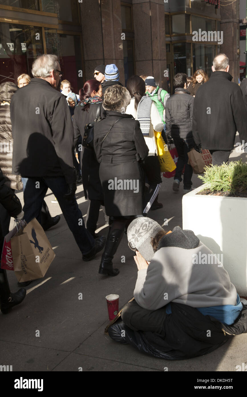 L'homme sans domicile s'assoit humblement sur le trottoir en demandant des dons pendant La saison des achats de vacances sur la 5ème Avenue à New York Banque D'Images