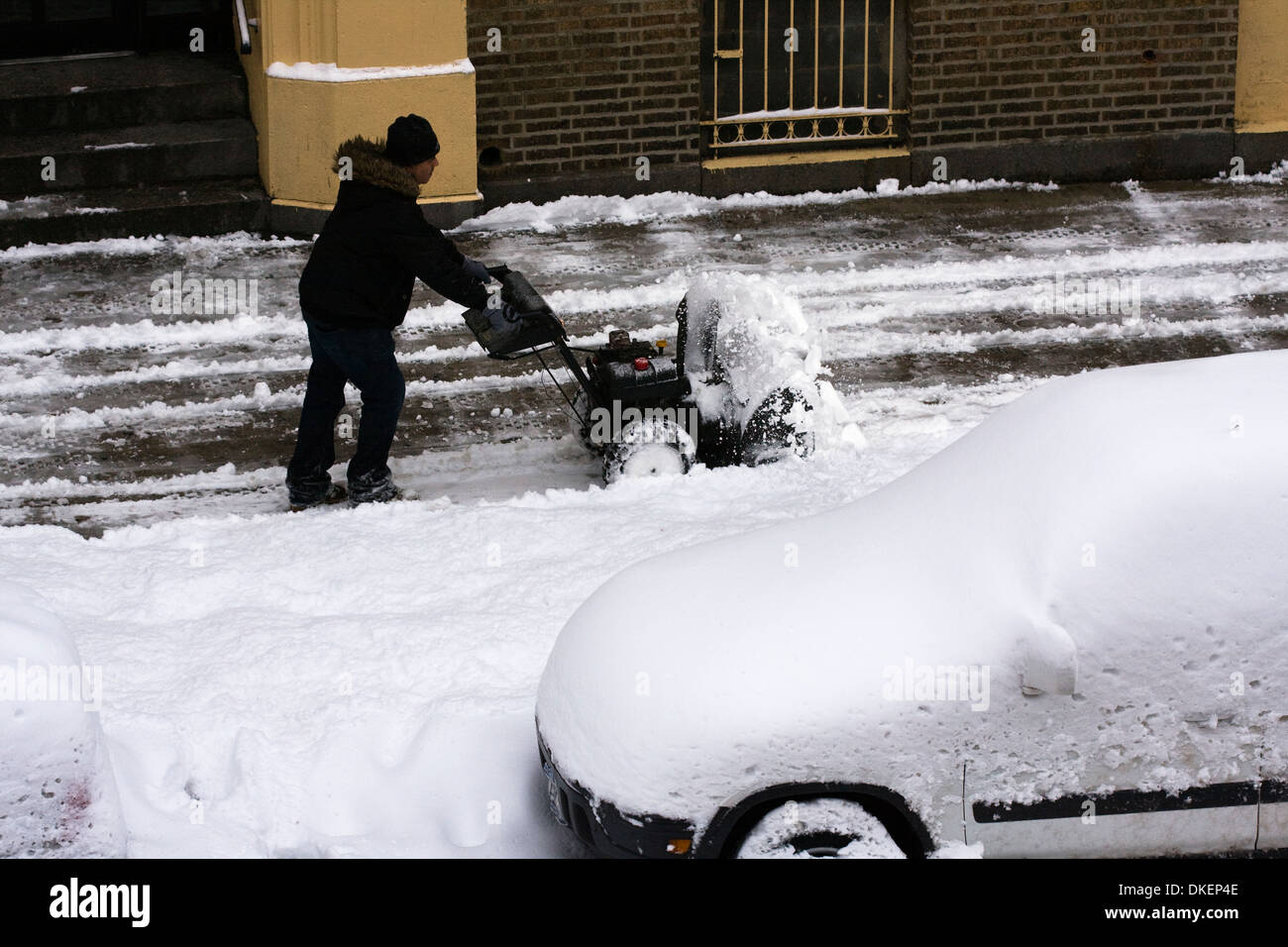 L'homme l'exploitation d'une souffleuse à neige pour dégager le trottoir après une tempête hivernale Banque D'Images