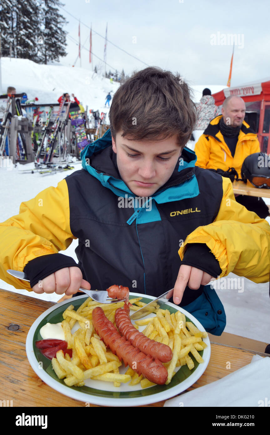 Woman tucks en saucisses et frites sur vacances de ski Banque D'Images