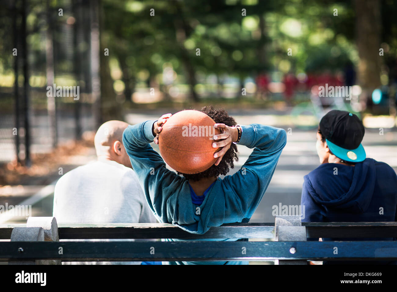 Les jeunes hommes assis sur le parc, un holding basketball Banque D'Images