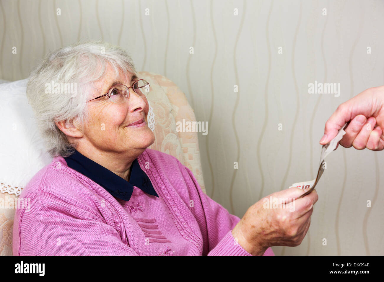 Heureuse femme sénior pensionnée OAP regardant sourire à quelqu'un un soignant et donnant de l'argent pour payer pour l'aide à la maison. La vie assistée coûte Angleterre Royaume-Uni Grande-Bretagne Banque D'Images