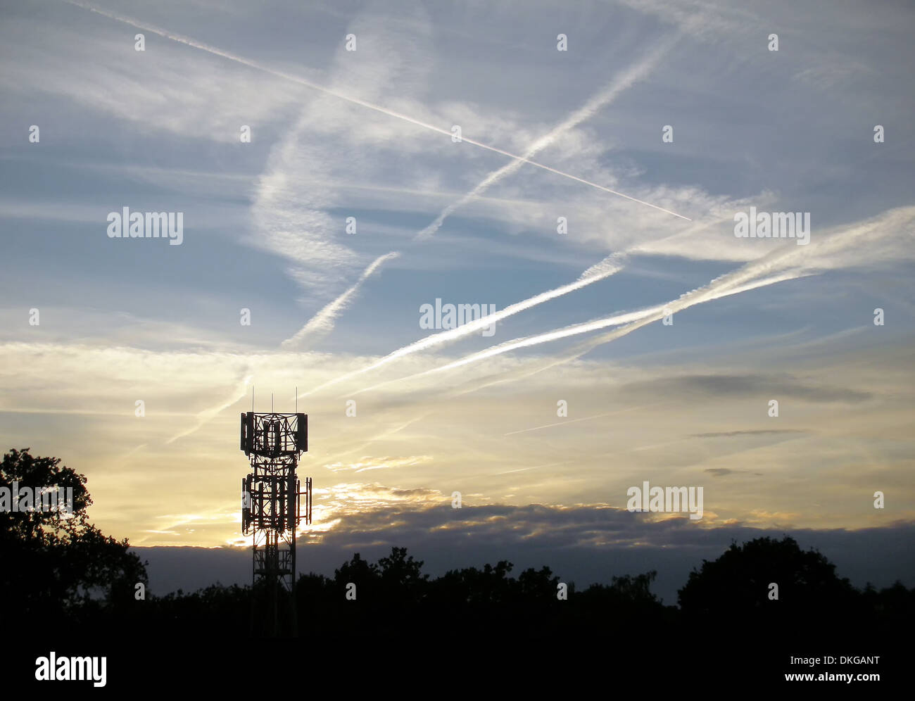 Coucher du soleil avec silhouette d'antenne de téléphonie mobile et des traînées de vapeur dans le ciel Banque D'Images