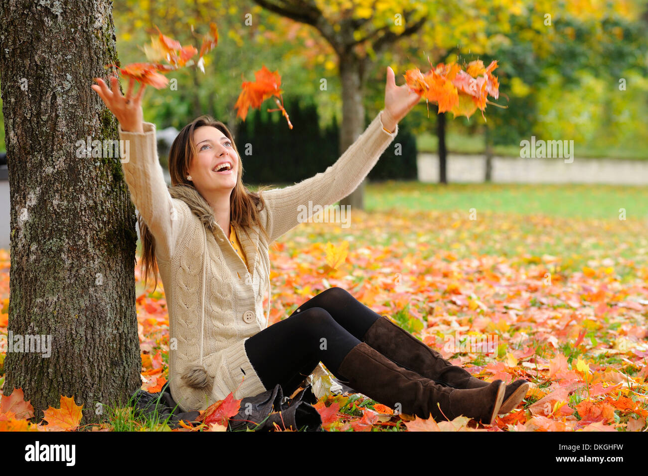 Jeune femme assise sous un arbre en automne Banque D'Images