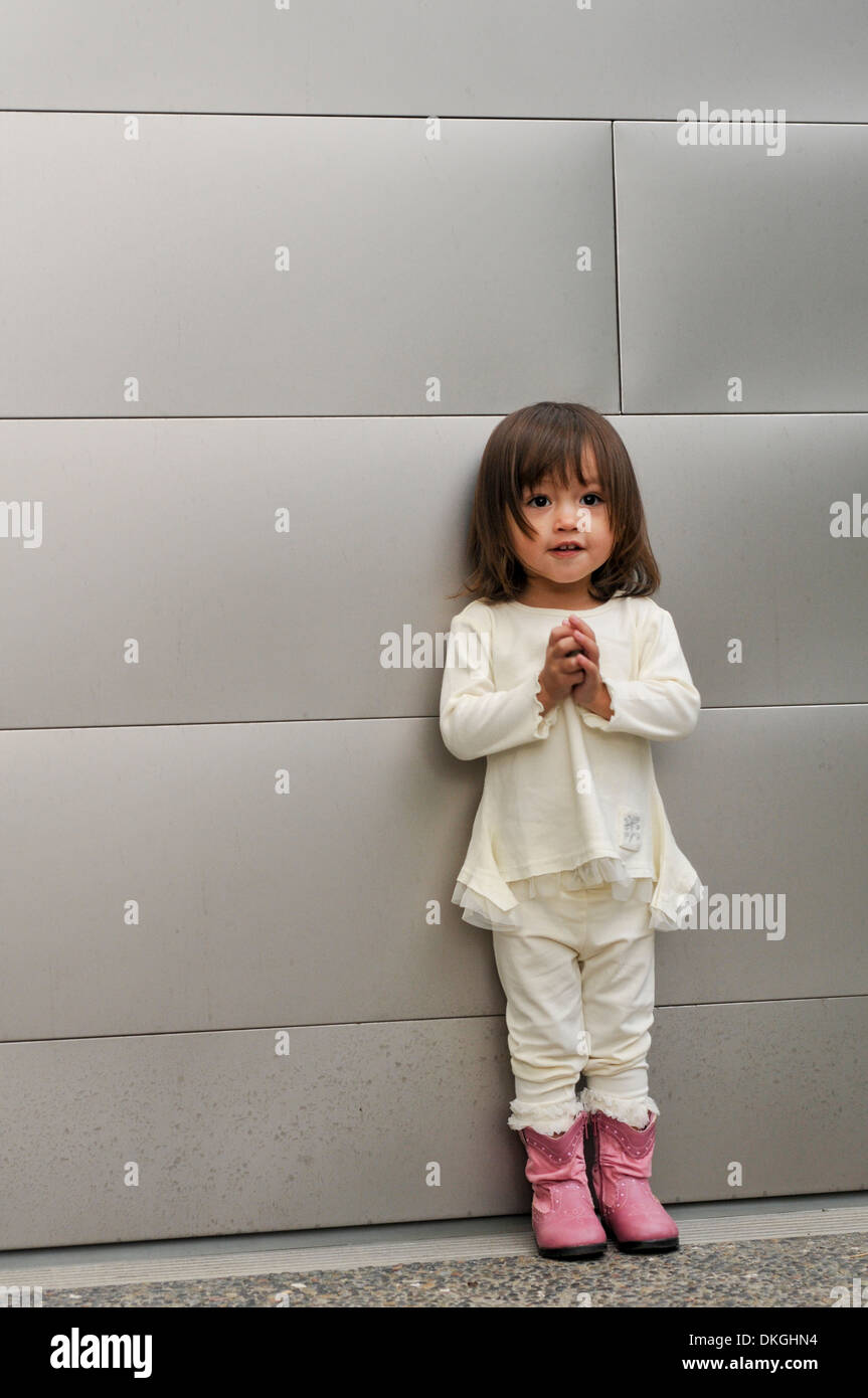 Un enfant de deux ans M. mixed race female rit tout en ayant sa photo prise. Elle a les cheveux bruns, est vêtu d'un costume blanc Banque D'Images