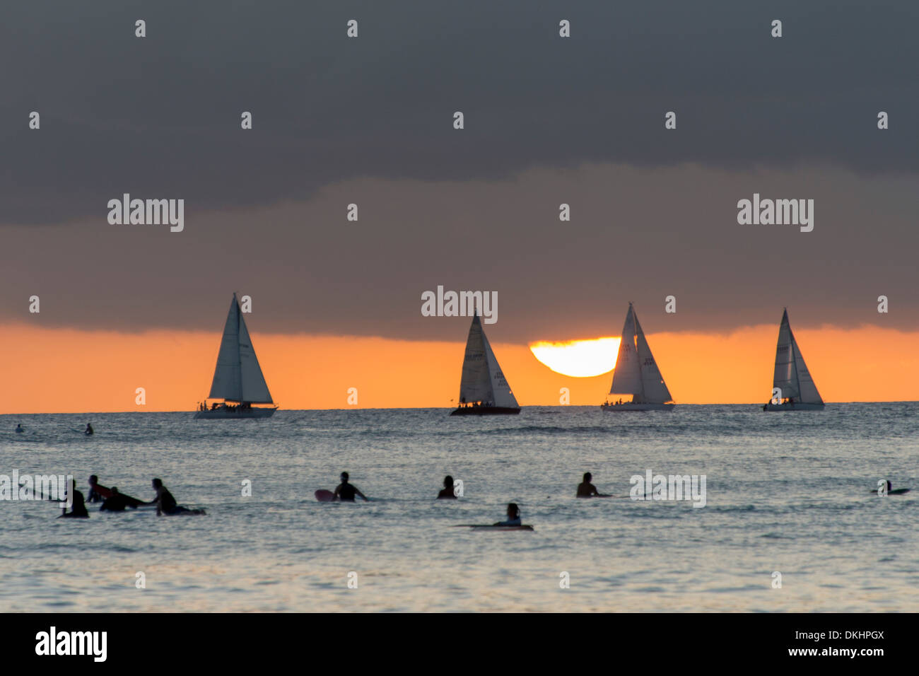 Les surfeurs sur la plage avec voiliers dans l'arrière-plan au coucher du soleil, Waikiki, Honolulu, Oahu, Hawaii, USA Banque D'Images