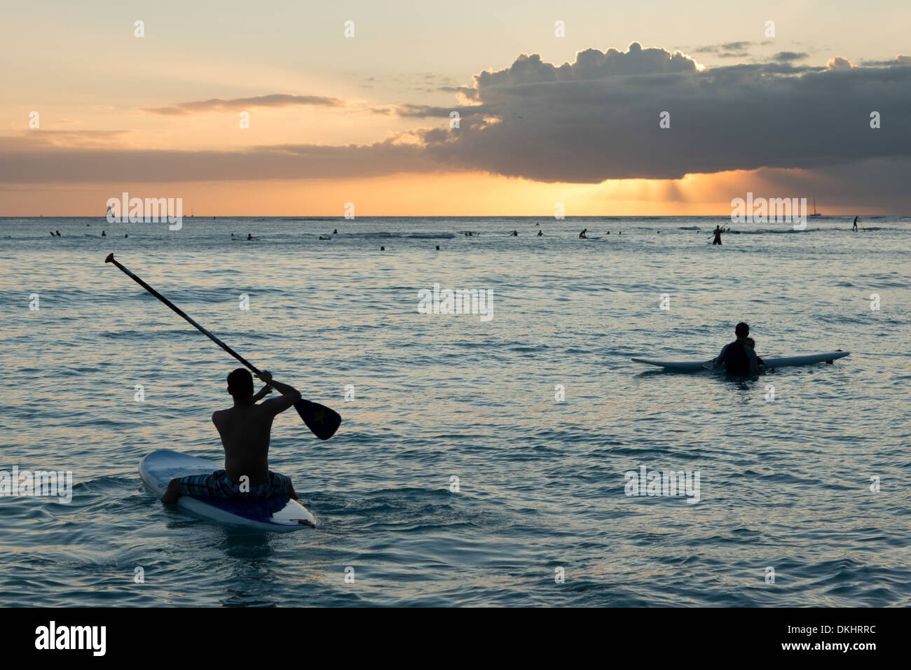 Les surfeurs et plaisanciers dans l'océan au coucher du soleil, Waikiki, Honolulu, Oahu, Hawaii, USA Banque D'Images