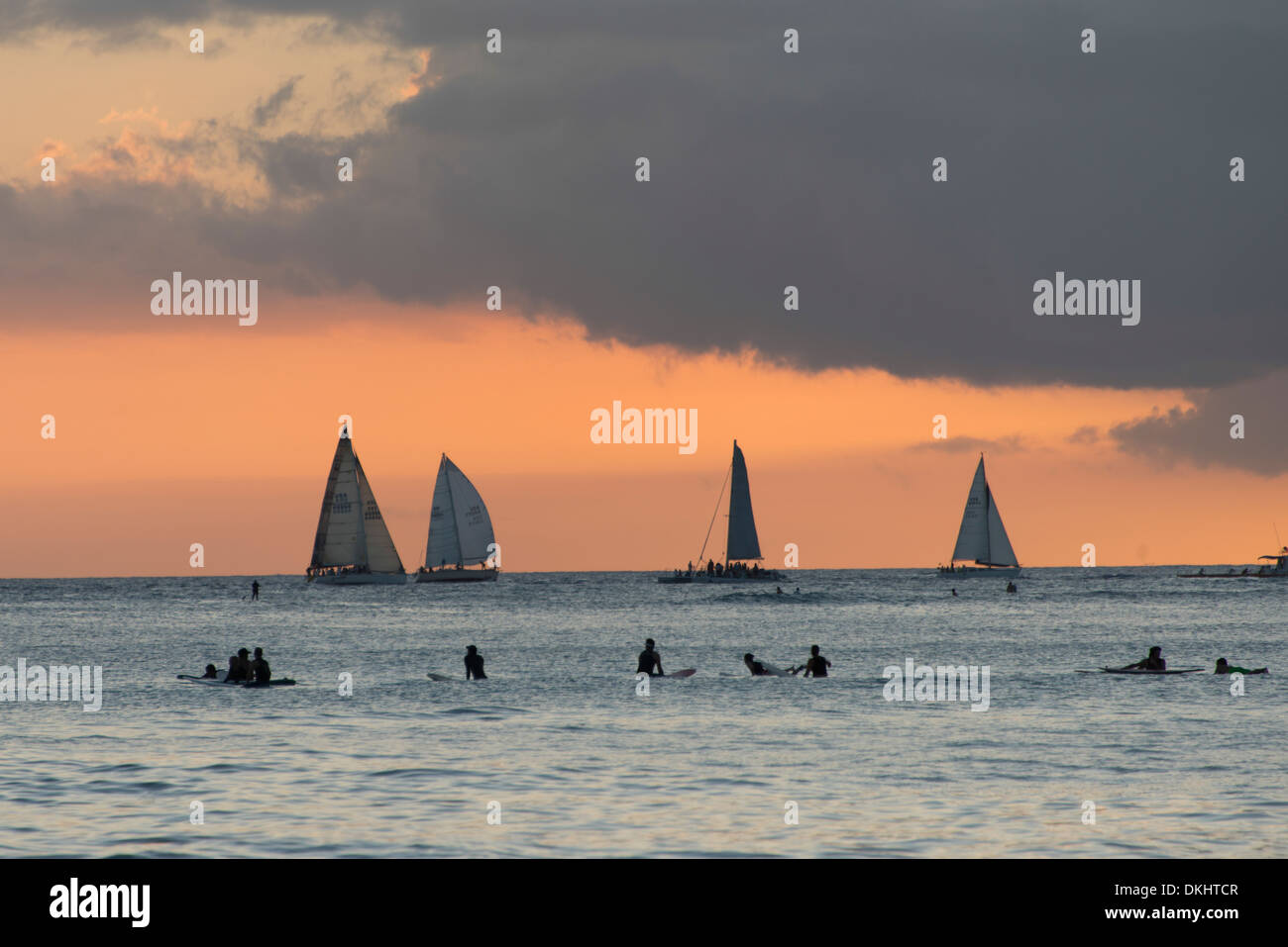 Les surfeurs sur la plage avec voiliers dans l'arrière-plan au coucher du soleil, Waikiki, Honolulu, Oahu, Hawaii, USA Banque D'Images