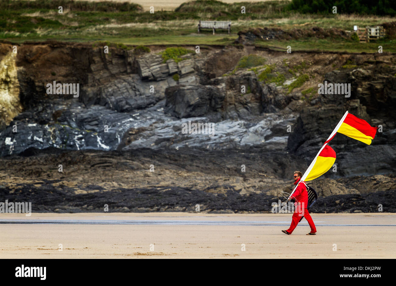 Lifeguard porte drapeaux waring à bord de l'eau à Cornwall Banque D'Images