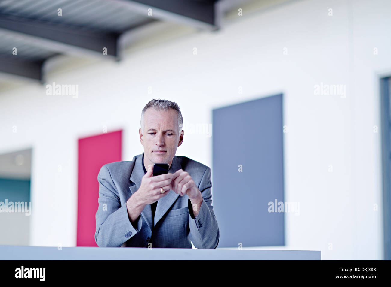 Businessman using cell phone in lobby Banque D'Images