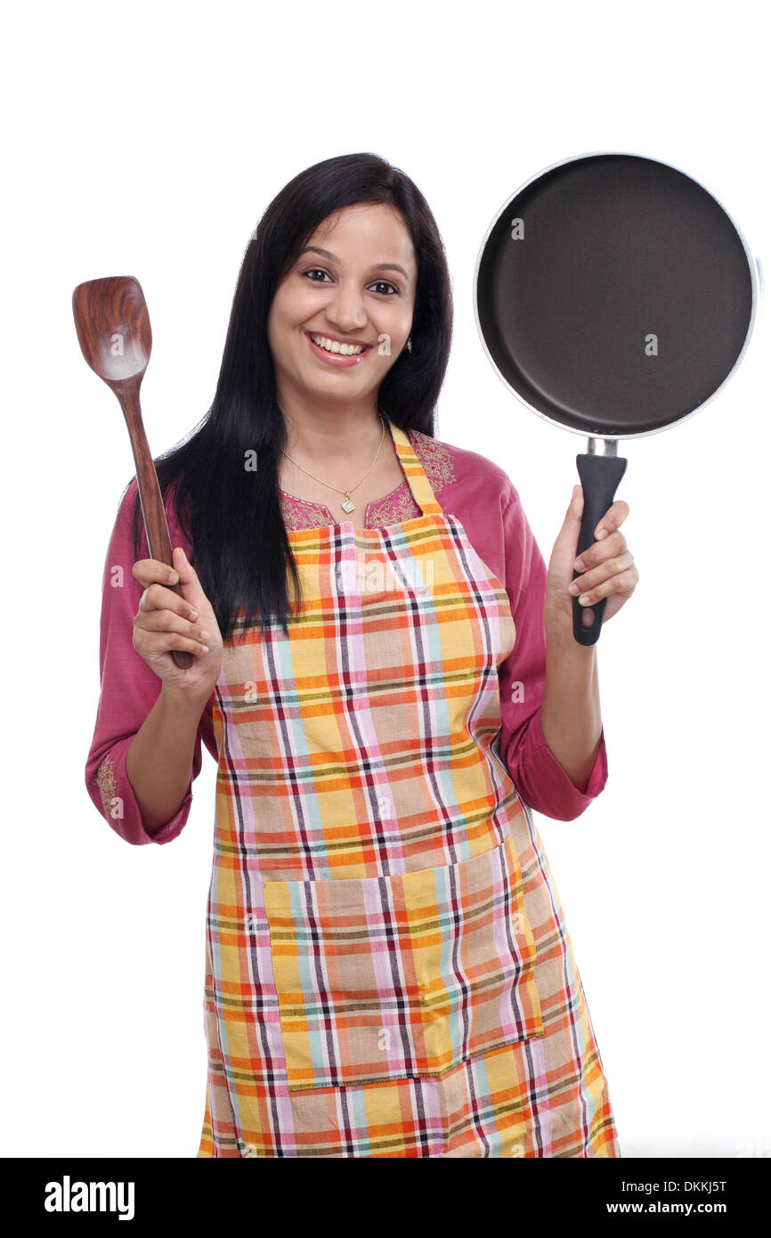 Jeune femme indienne holding ustensile de cuisine contre fond blanc Banque D'Images