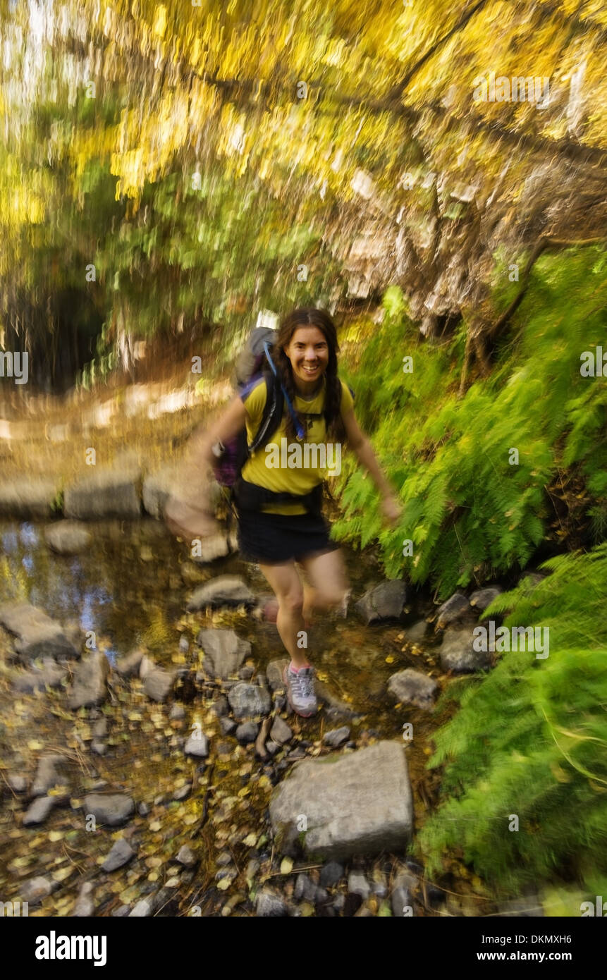 Femme randonneuse traversant un ruisseau rapide avec motion blur Banque D'Images