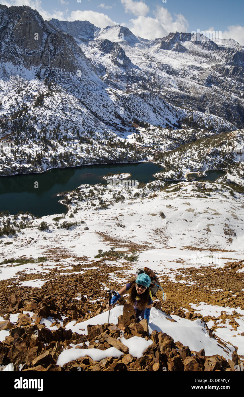 Woman climbing up Chocolate pic dans les montagnes de la Sierra Nevada avec le lac Long ci-dessous sa Banque D'Images