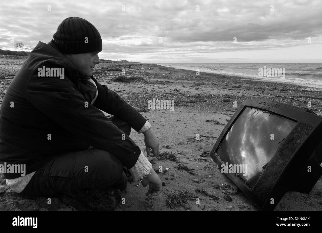 L'homme regardant la télévision est échoué sur une plage. Banque D'Images