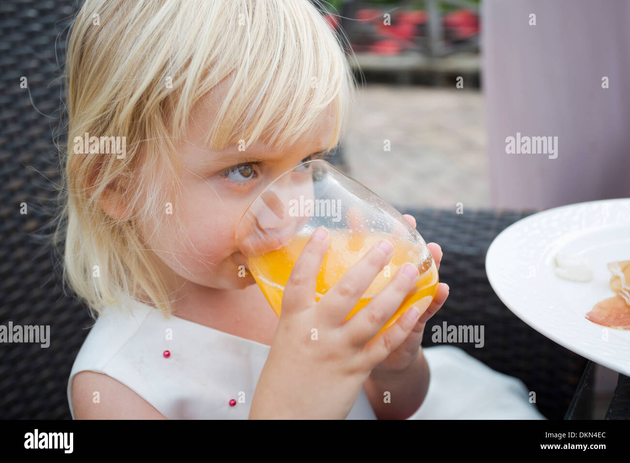 Jolie petite fille assise à l'extérieur de boire du jus Banque D'Images