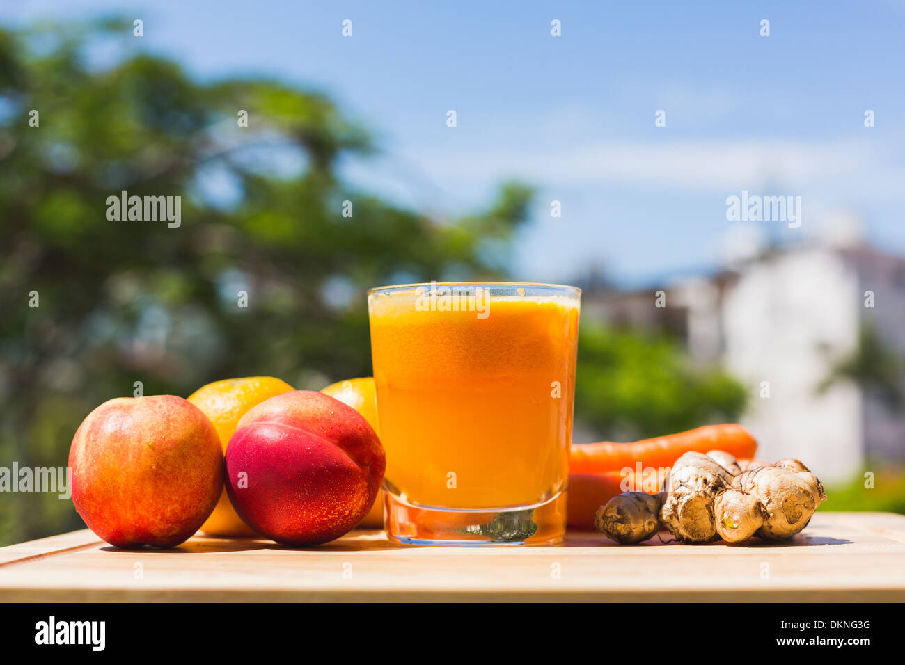 Fruits, légumes et verre de jus d'orange à l'extérieur avec des arbres et du ciel en arrière-plan Banque D'Images