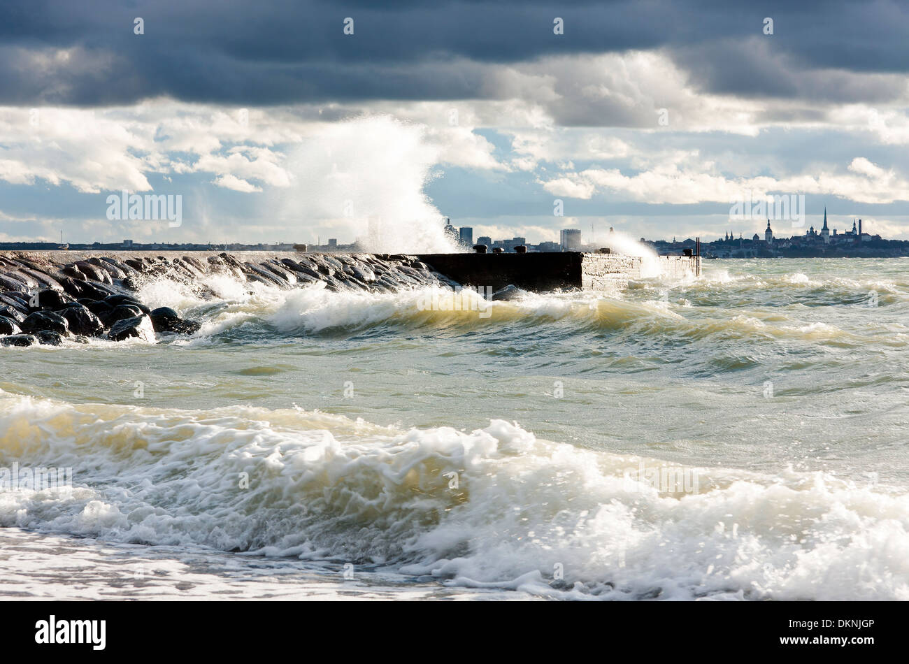 Pier ou quay dans une mer houleuse et turbulent à un sombre mais mais journée ensoleillée. Silhouette ville de Tallinn en arrière-plan. Banque D'Images