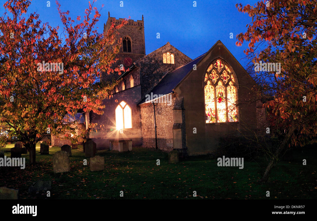 Brancaster, lumières de l'Église vitrail lumineux à travers la nuit, Norfolk, Angleterre, Royaume-Uni Banque D'Images