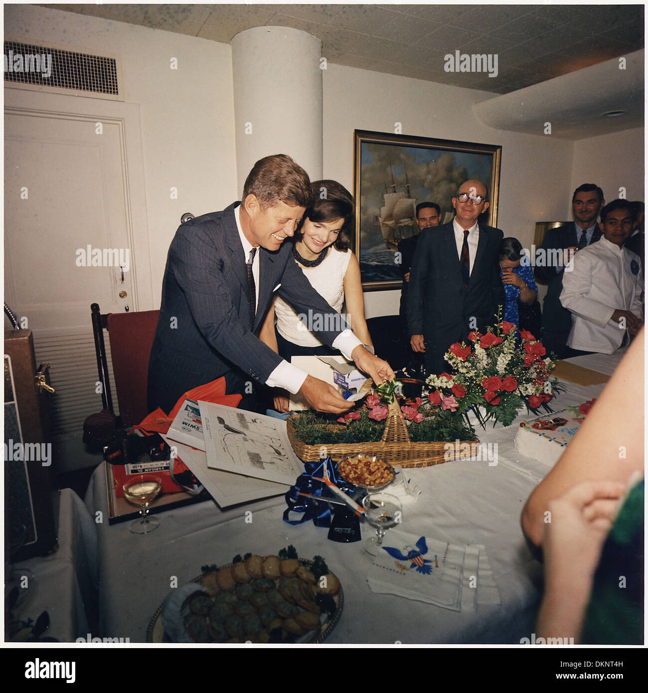 Cette image capture le président John F. Kennedy, son épouse Jacqueline et le personnel de la Maison Blanche lors d'une célébration d'anniversaire pour le président. La photo met en lumière un moment clé de la vie sociale de l’administration Kennedy. Banque D'Images