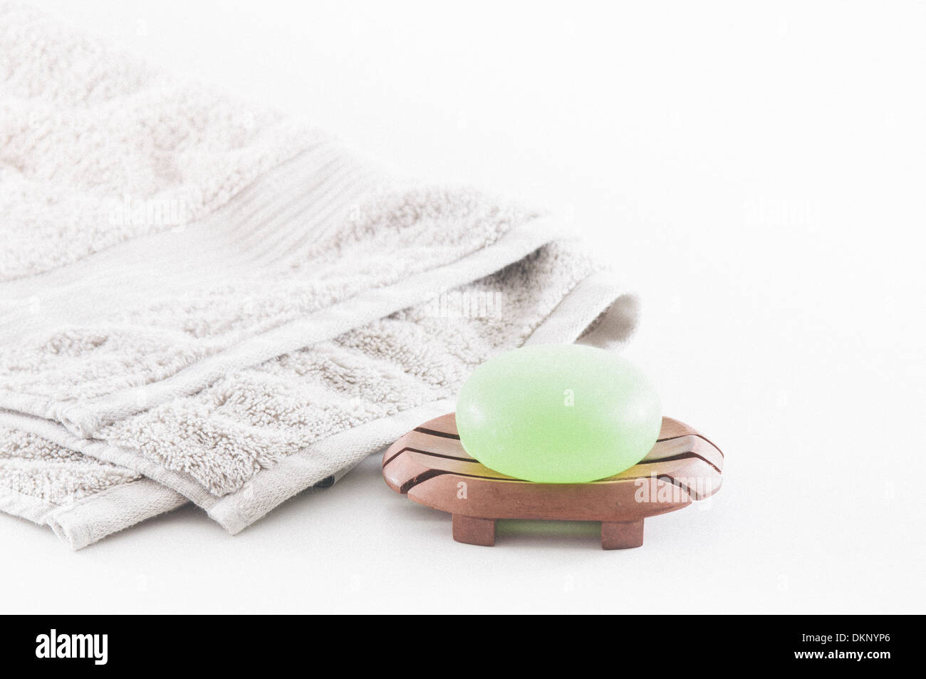 Savon vert vif et lotions avec une serviette derrière eux impliquant une belle journée spa isolated on white Banque D'Images