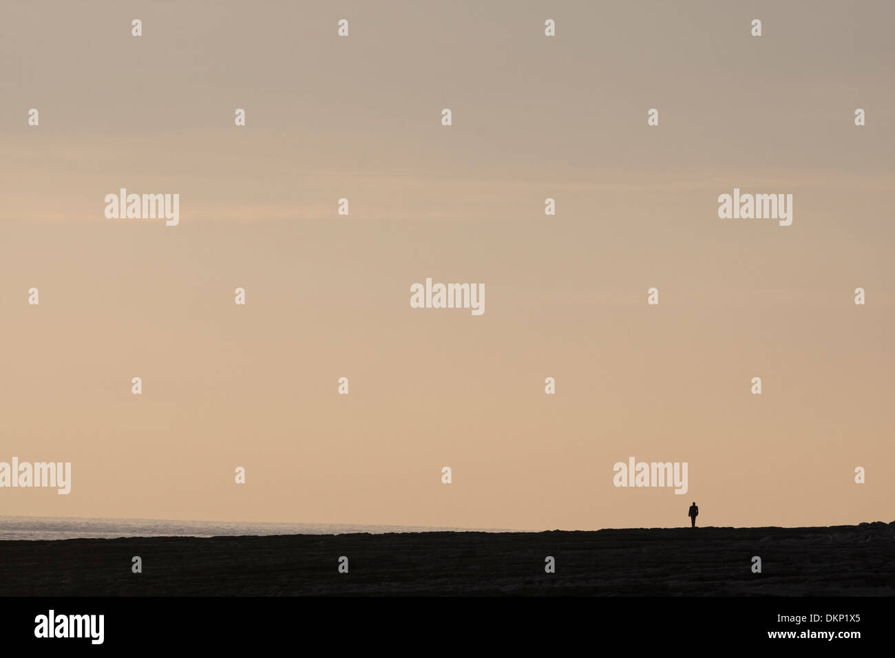 Silhouette solitaire lointain petit sur la plage au crépuscule Banque D'Images