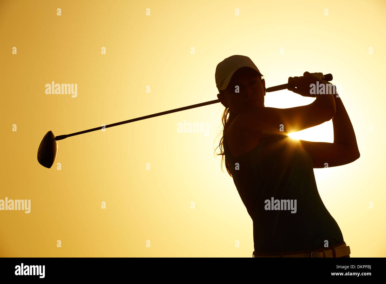 Silhouette of woman playing golf on course Banque D'Images