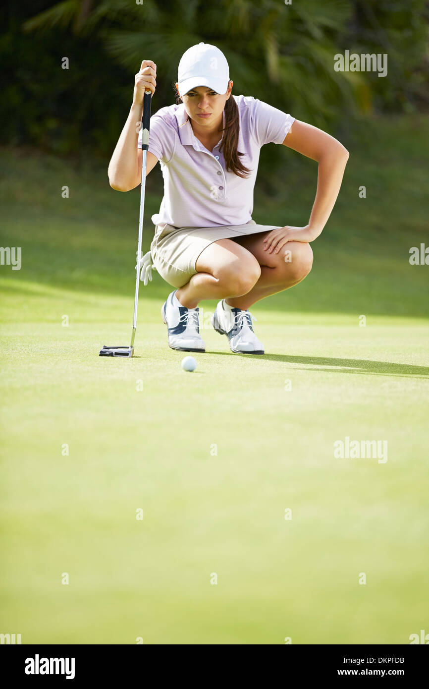 Woman preparing to putt on golf course Banque D'Images