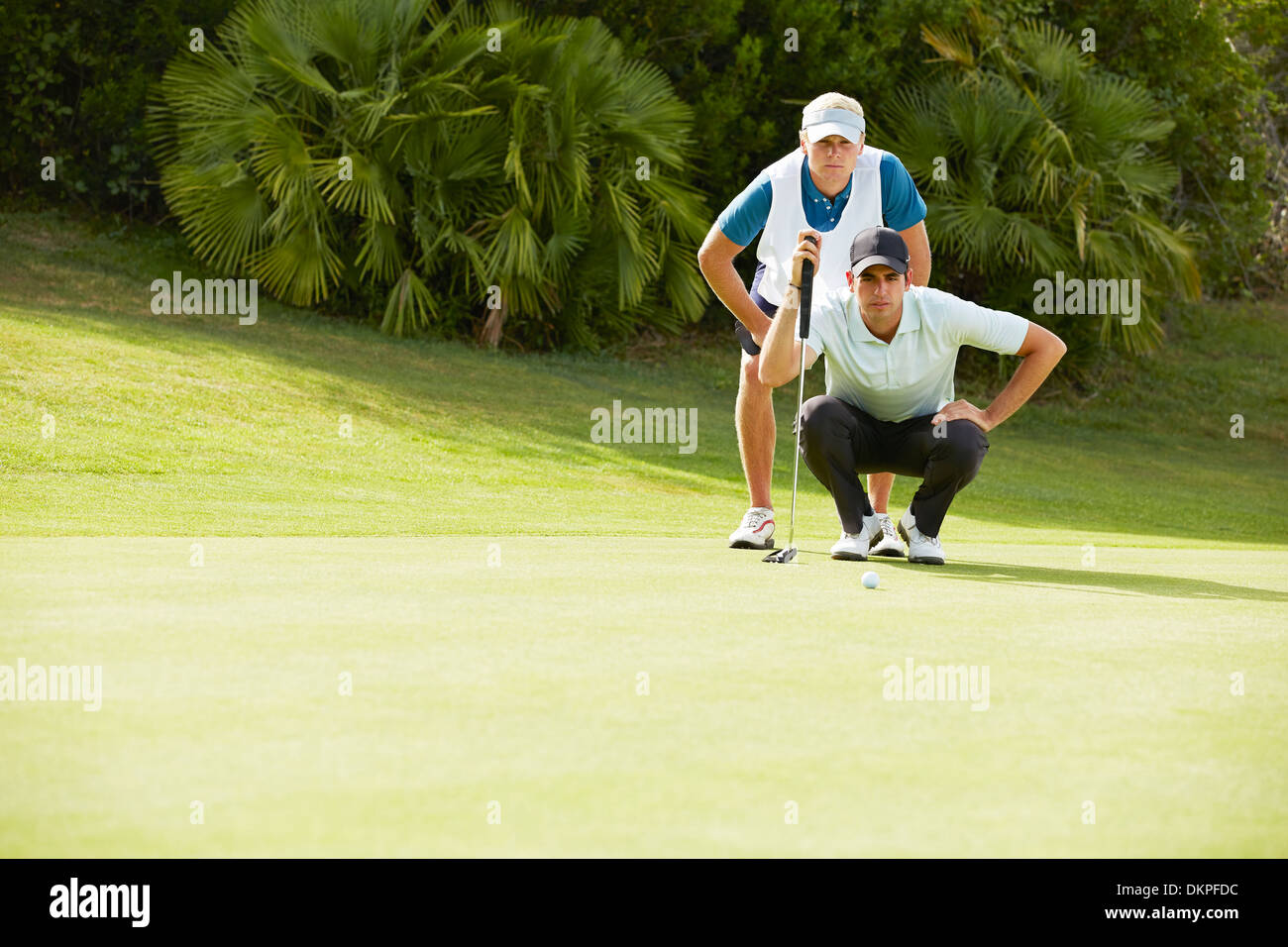 Caddy et golfeur prépare à putt Banque D'Images
