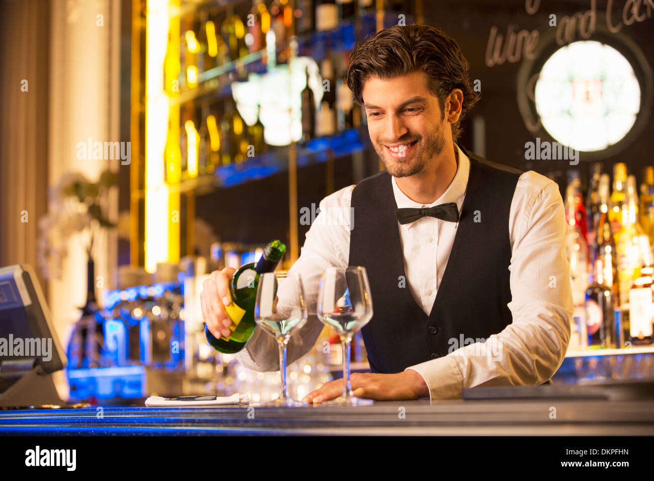 Bien habillé bartender pouring wine Banque D'Images