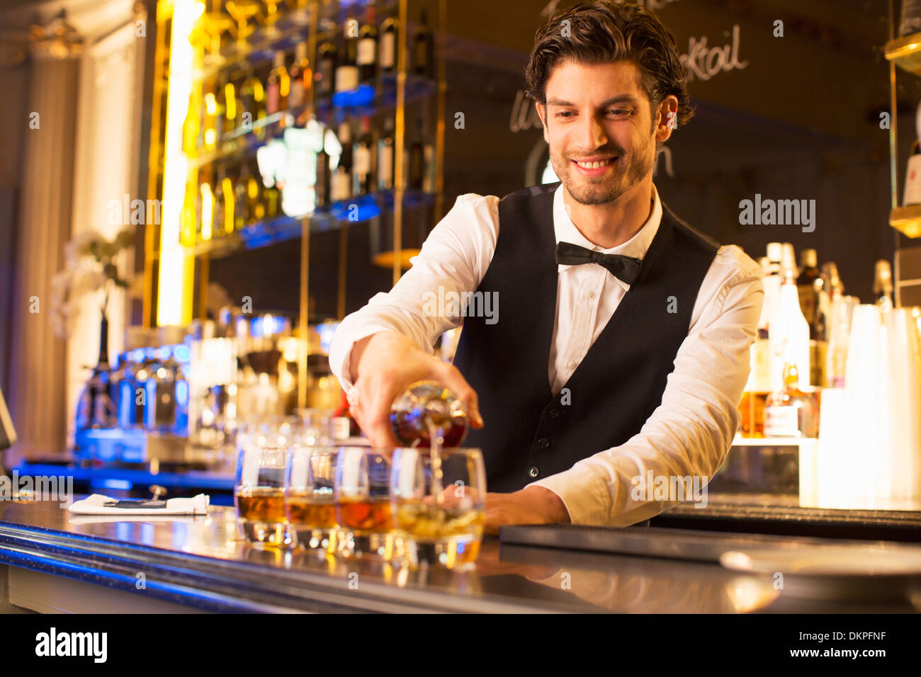 Bien habillé bartender pouring bourbon au bar de luxe Banque D'Images