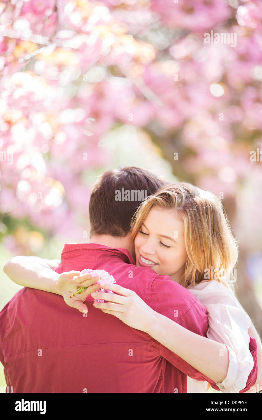 Couple hugging under tree with pink blossoms Banque D'Images