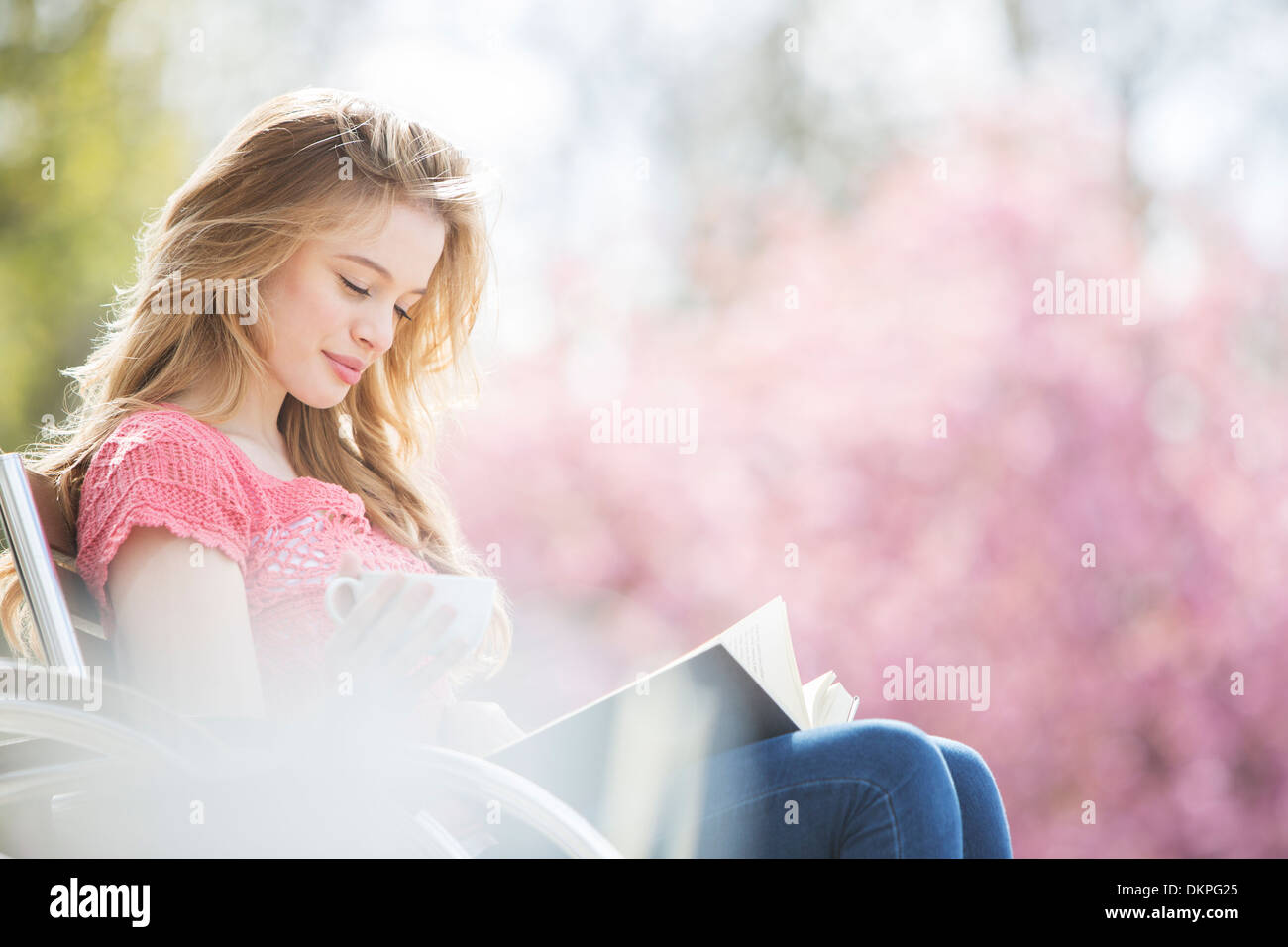 Woman Reading book on park bench Banque D'Images