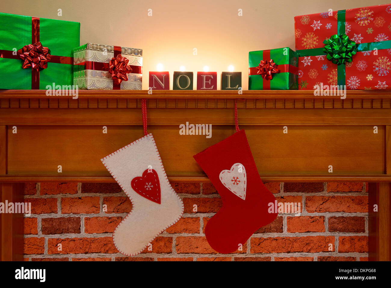Des bas de Noël suspendues sur la cheminée avec gift wrapped presents et Noel bougies Banque D'Images