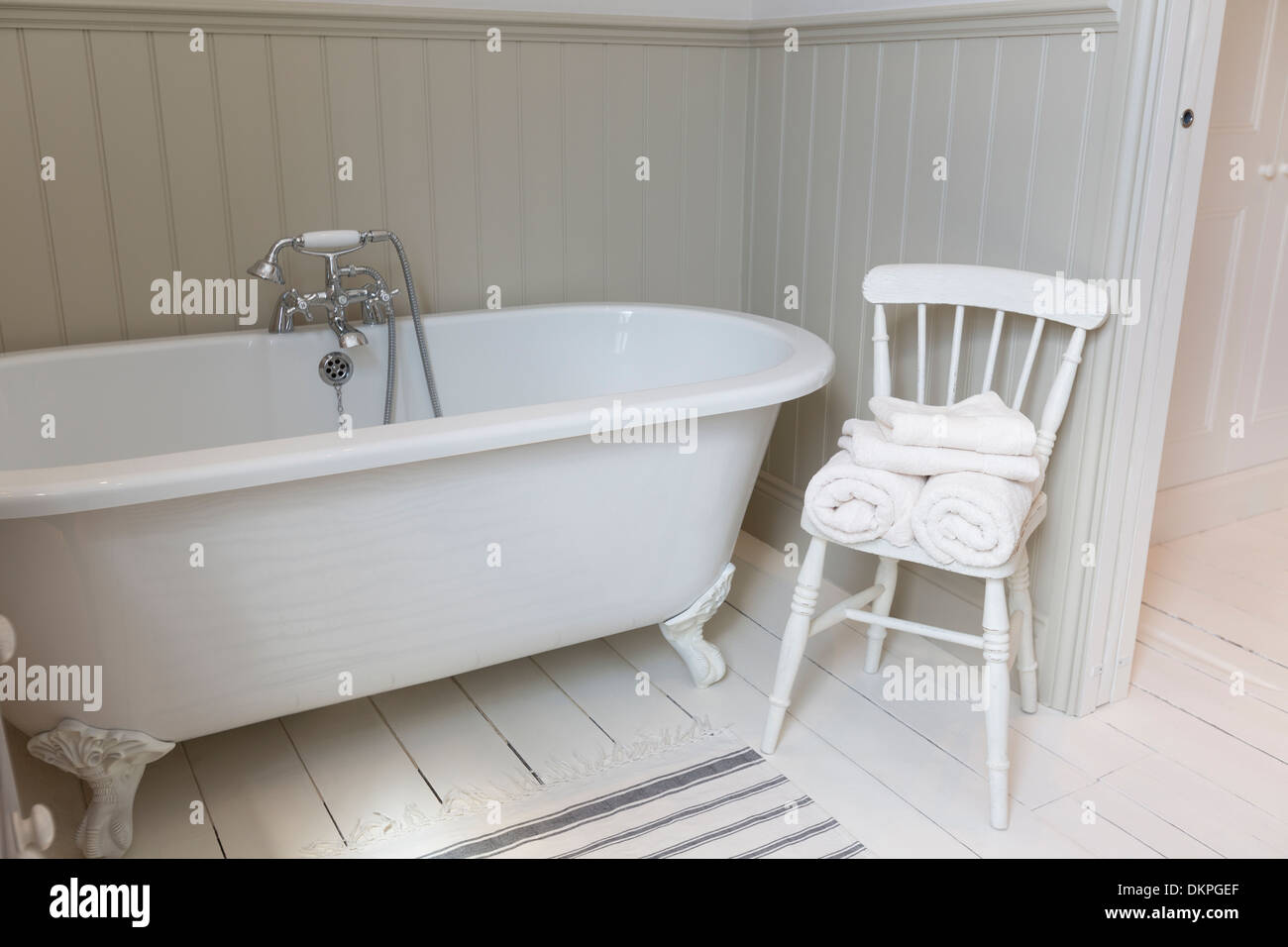Une baignoire et une chaise dans une salle de bains privative ornée Banque D'Images