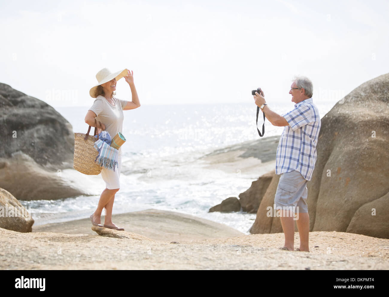 Homme plus âgé prendre des photos de votre petite amie sur la plage Banque D'Images