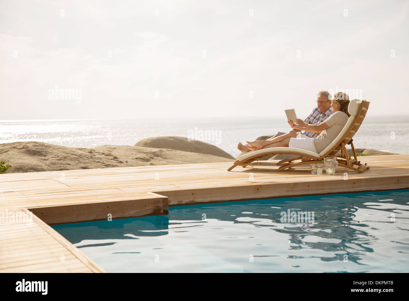 Vieux couple relaxing by pool Banque D'Images