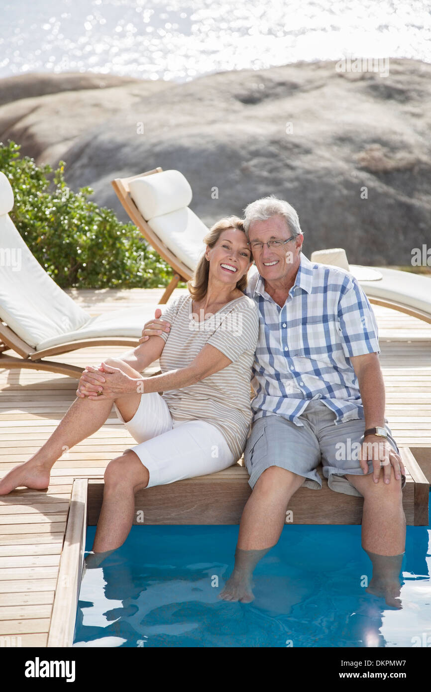 Vieux couple relaxing by swimming pool Banque D'Images