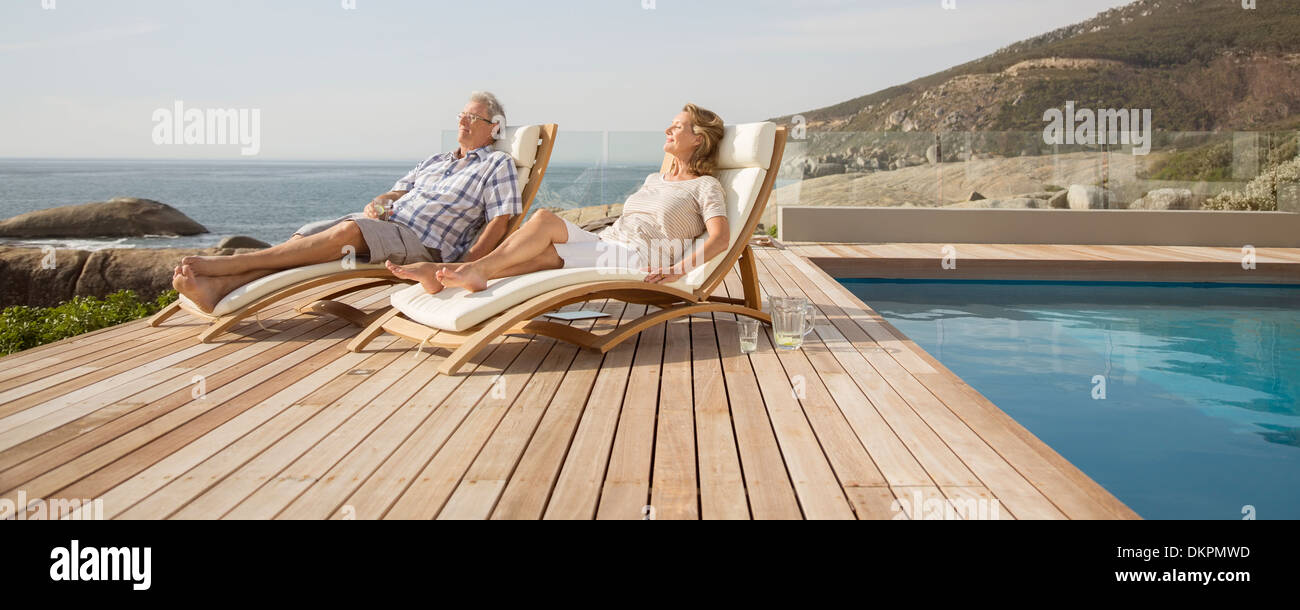 Vieux couple relaxing in chaises de piscine par Banque D'Images
