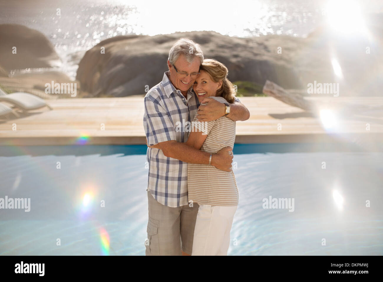Vieux couple hugging by pool Banque D'Images