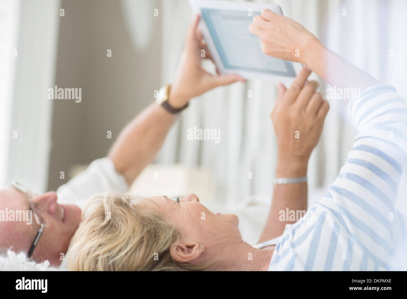 Vieux couple using digital tablet on bed Banque D'Images