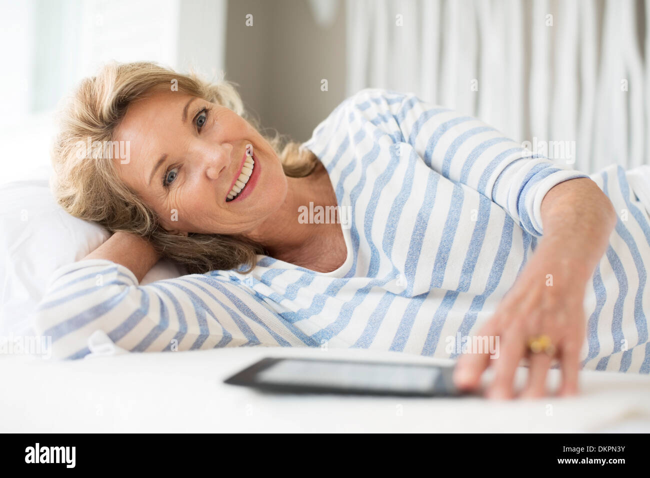 Older woman using digital tablet on bed Banque D'Images