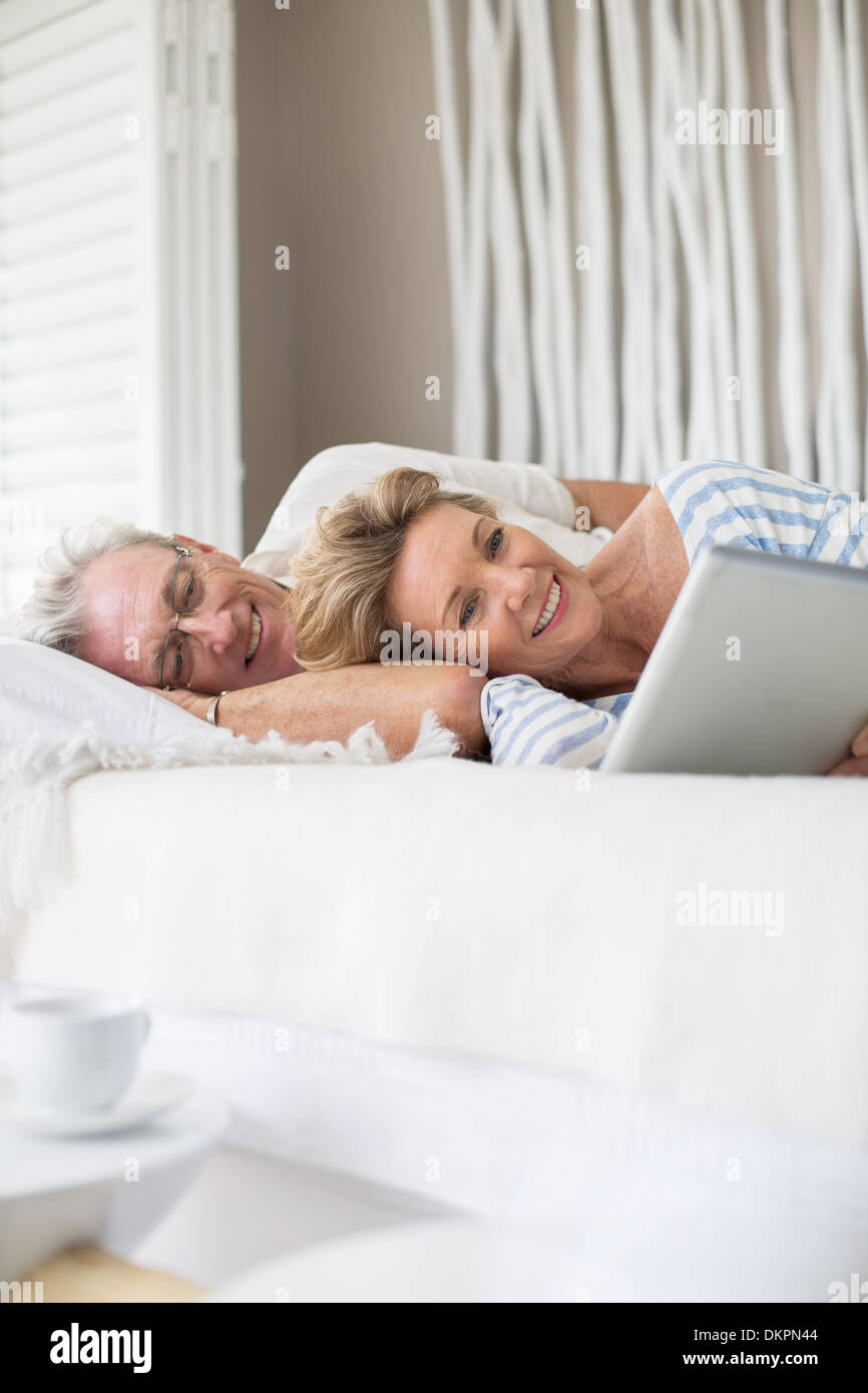 Vieux couple using digital tablet on bed Banque D'Images