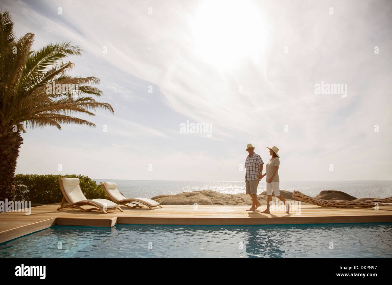 Vieux couple relaxing together by pool Banque D'Images