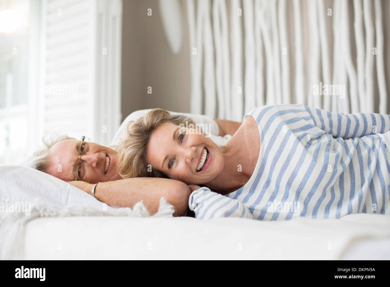 Vieux couple relaxing together on bed Banque D'Images