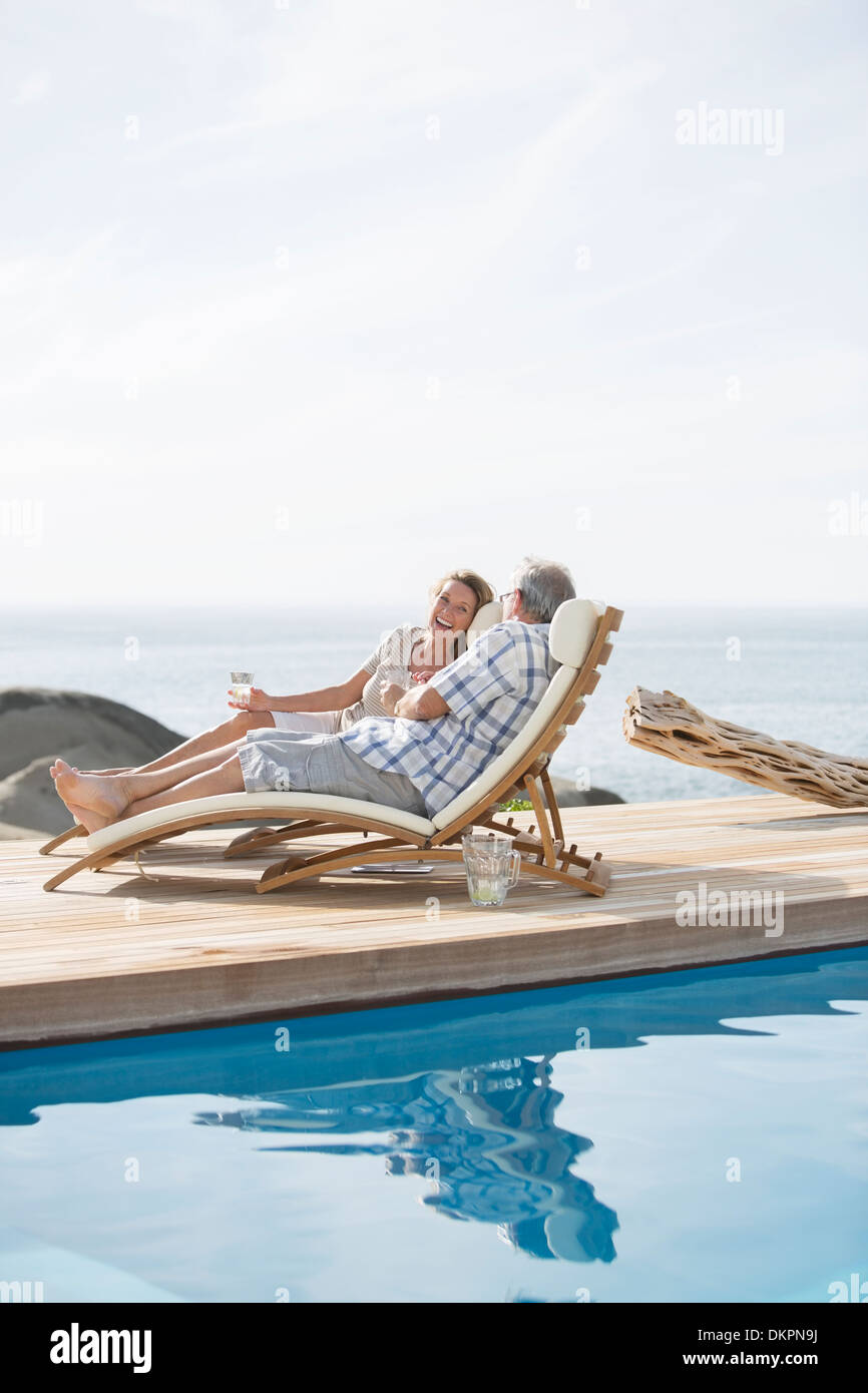 Vieux couple relaxing by pool Banque D'Images