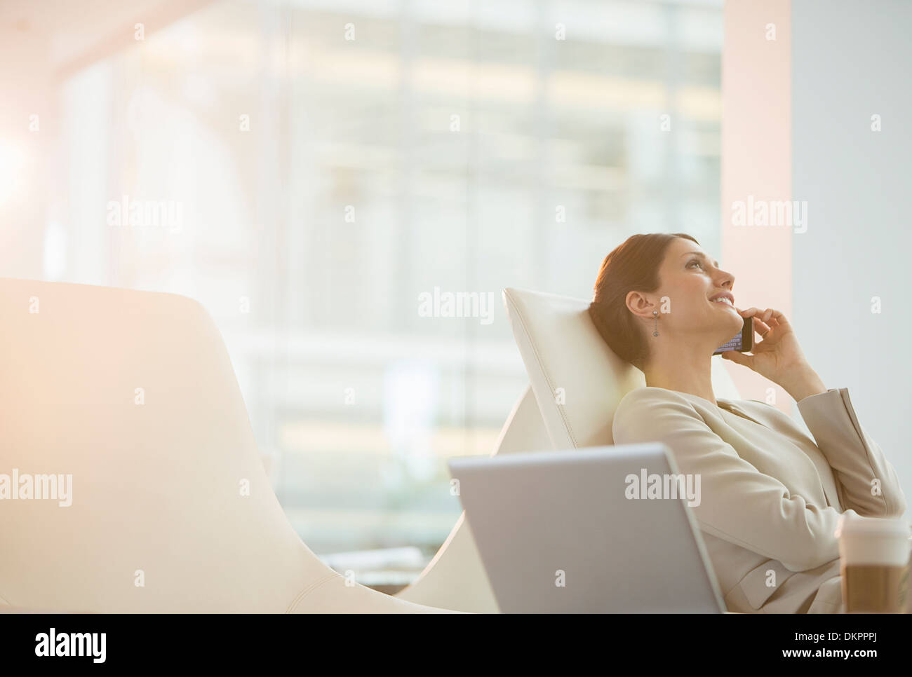 Businesswoman talking on cell phone in office Banque D'Images