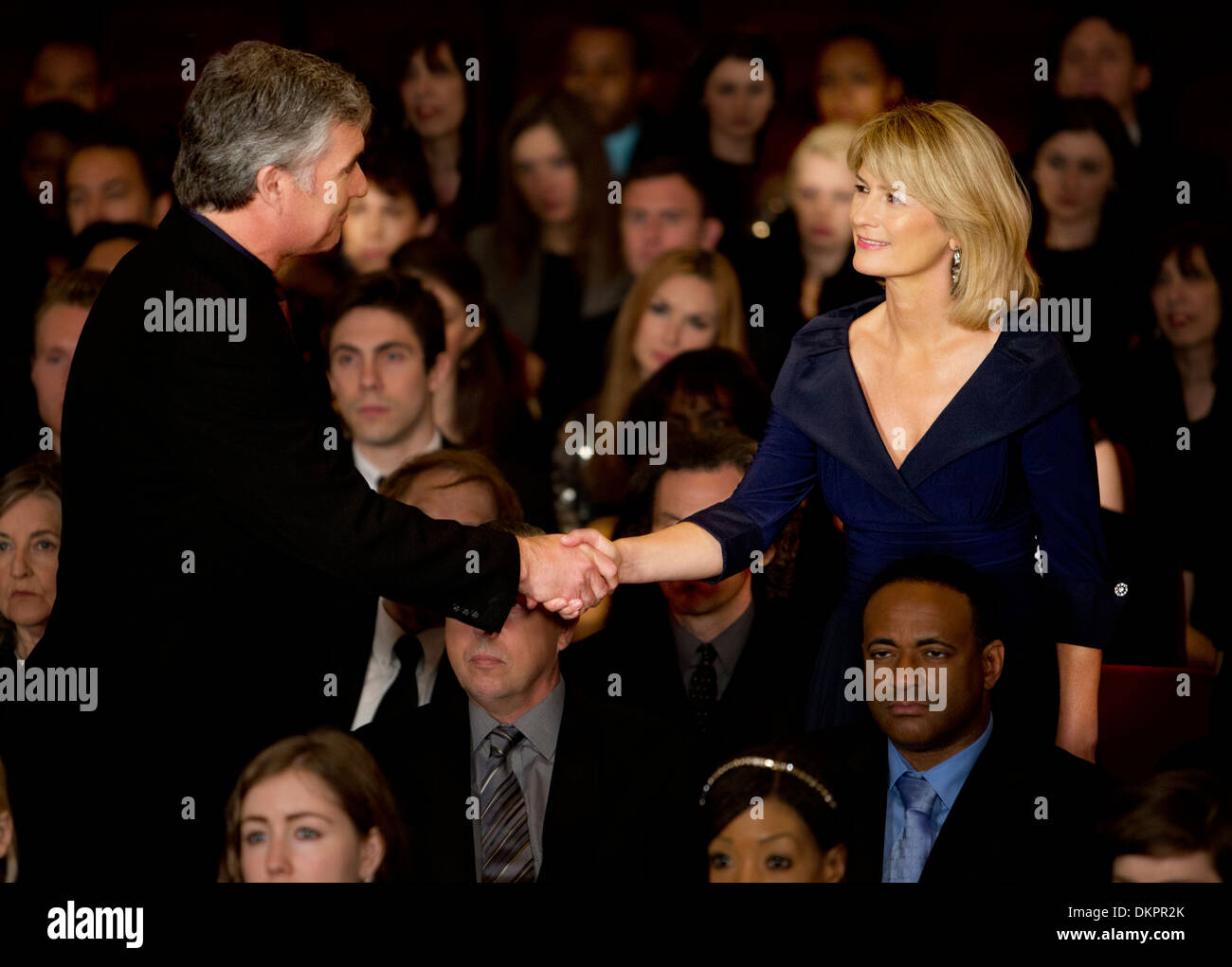 L'homme et la femme handshaking in theater audience Banque D'Images