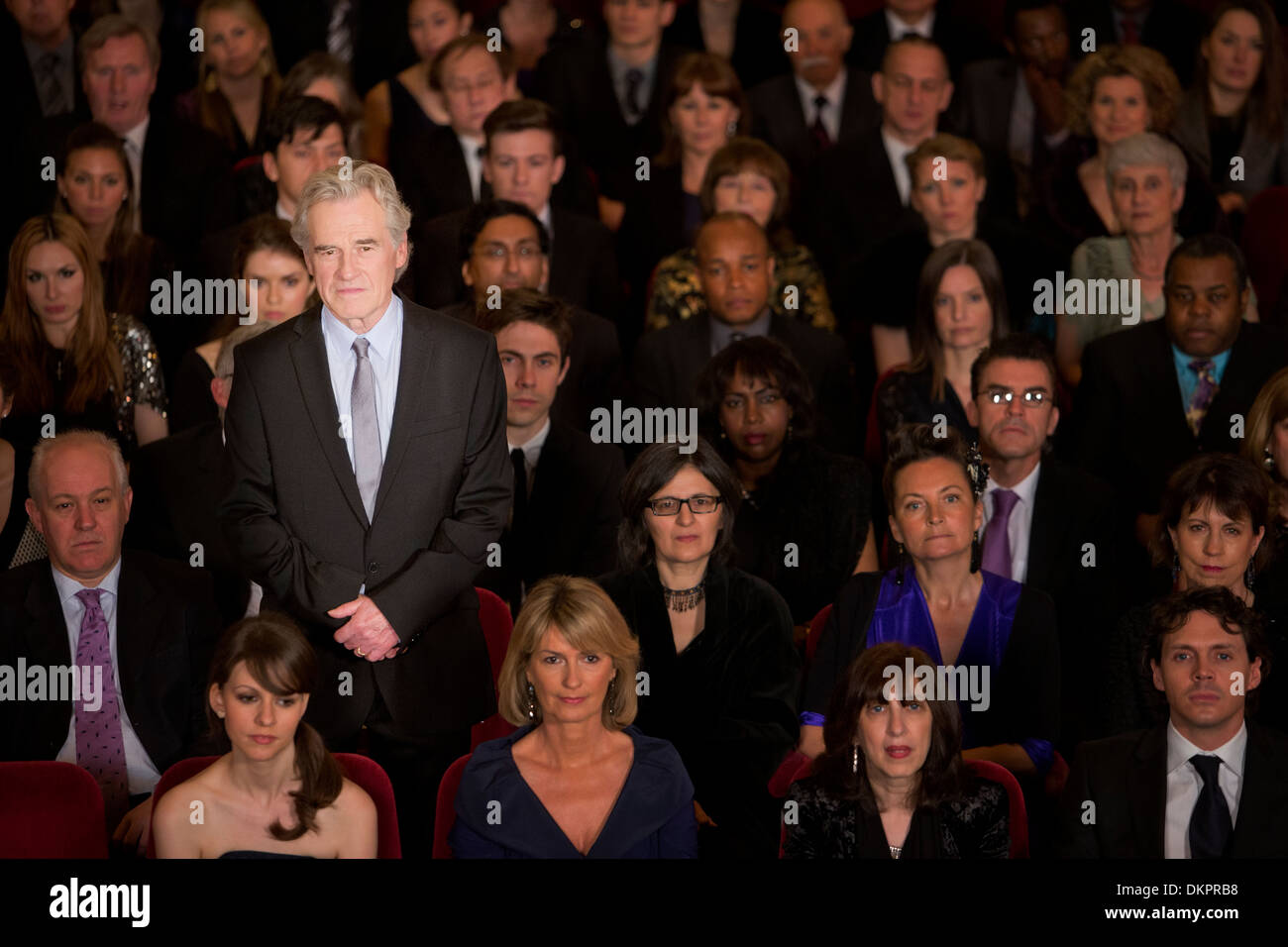 Serious man standing in theater audience Banque D'Images