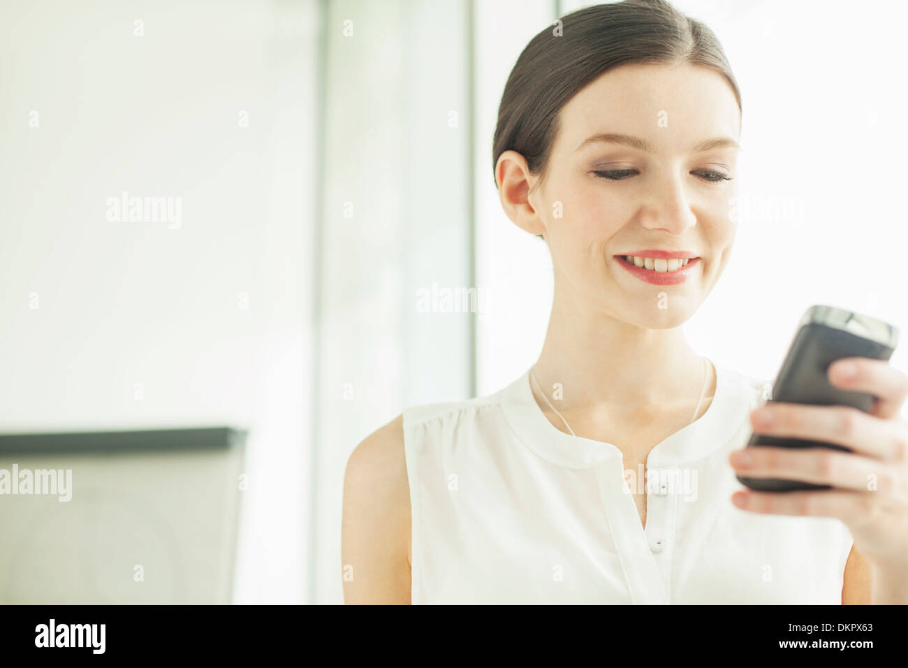 Businesswoman using cell phone in office Banque D'Images