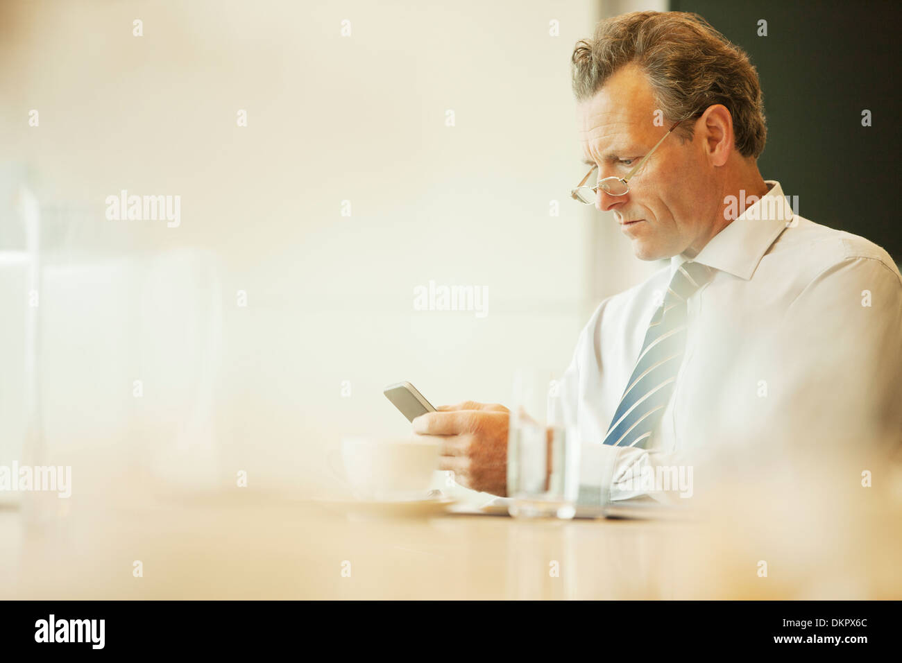 Businessman using cell phone in cafe Banque D'Images